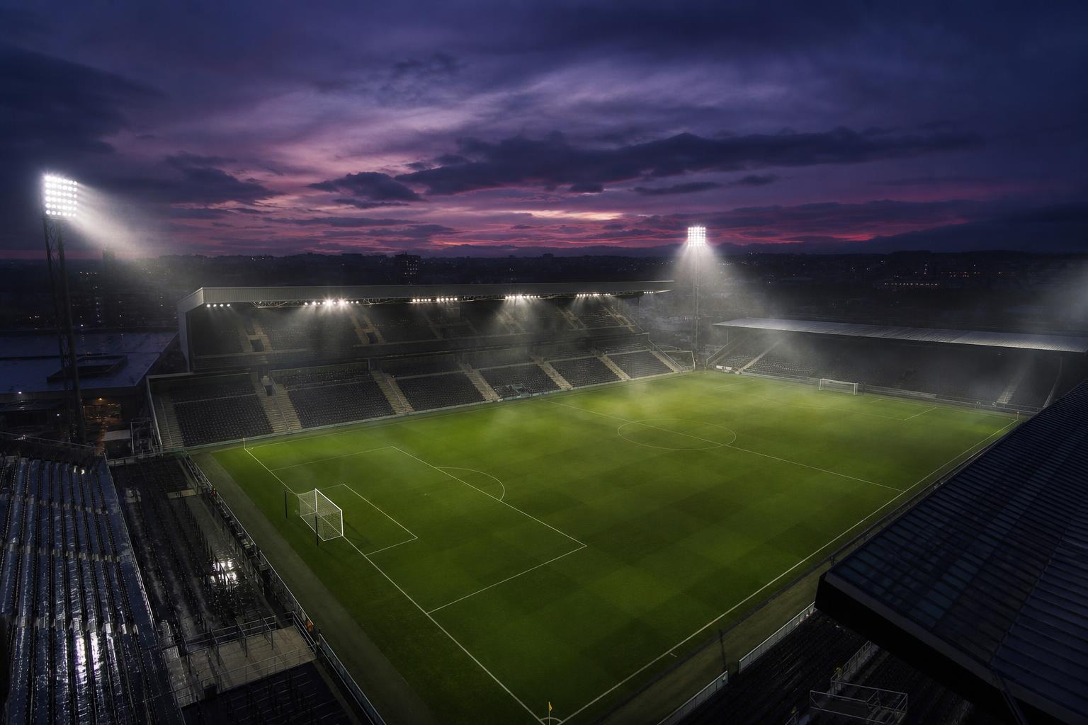 Estádio de futebol iluminado ao entardecer visto do alto
